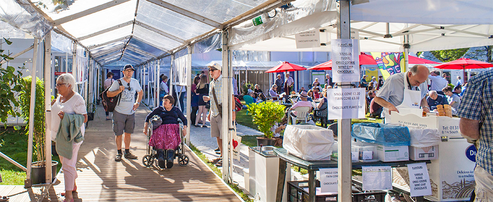 Photo: A man walking and a woman in a wheelchair at the Edinburgh International Book Festival